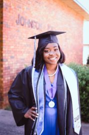 Zanesha Rhodes poses in her graduation regalia outside Johnson Hall, where she spent much of her time as a College of Education student.