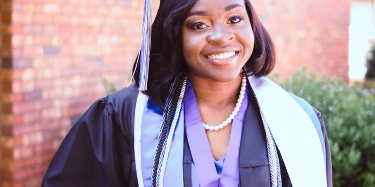 Zanesha Rhodes poses in her graduation regalia outside Johnson Hall, where she spent much of her time as a College of Education student.