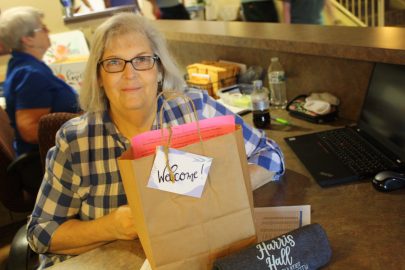 Peggy Oliver sits at the front desk of the women's dormitory with a gift bag to welcome freshmen girls to their new home away from home.