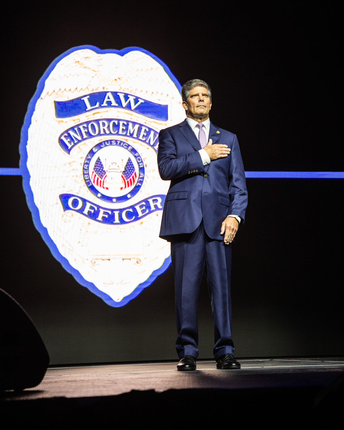 Hal Taylor, secretary of ALEA puts his hand over his heart to honor law enforcement officers being honored at the Benefit Dinner.