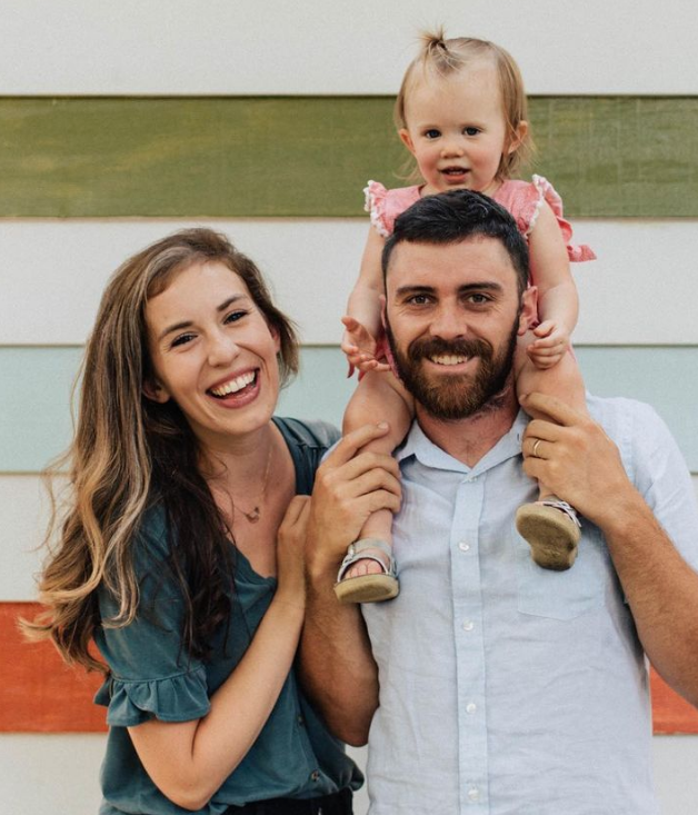 Laura Jean Bell is the Young Alumna for English. She is a mom, a blogger, reality investor and podcast talent. She poses with her husband, Cody and her daughter Emmy Lou who is sitting on Cody's shoulders.