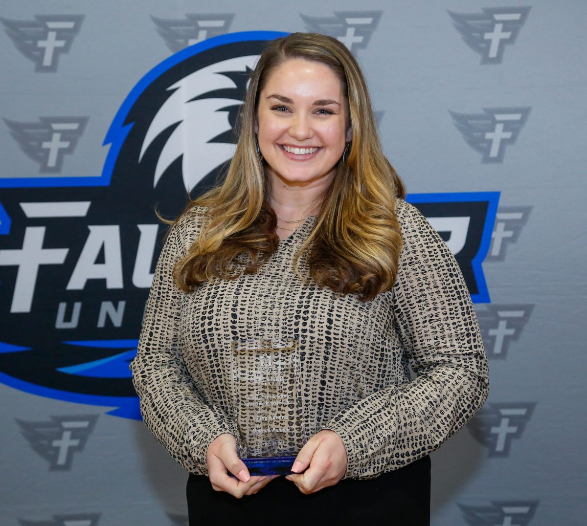 Hannah Putman stands with her award at the Marketplace Faith Friday Forums.As a microbiologist with the Alabama Department of Public Health, (ADPH) Faulkner alumna Hannah Putman is working to combat illnesses and make a positive difference in people's lives.  