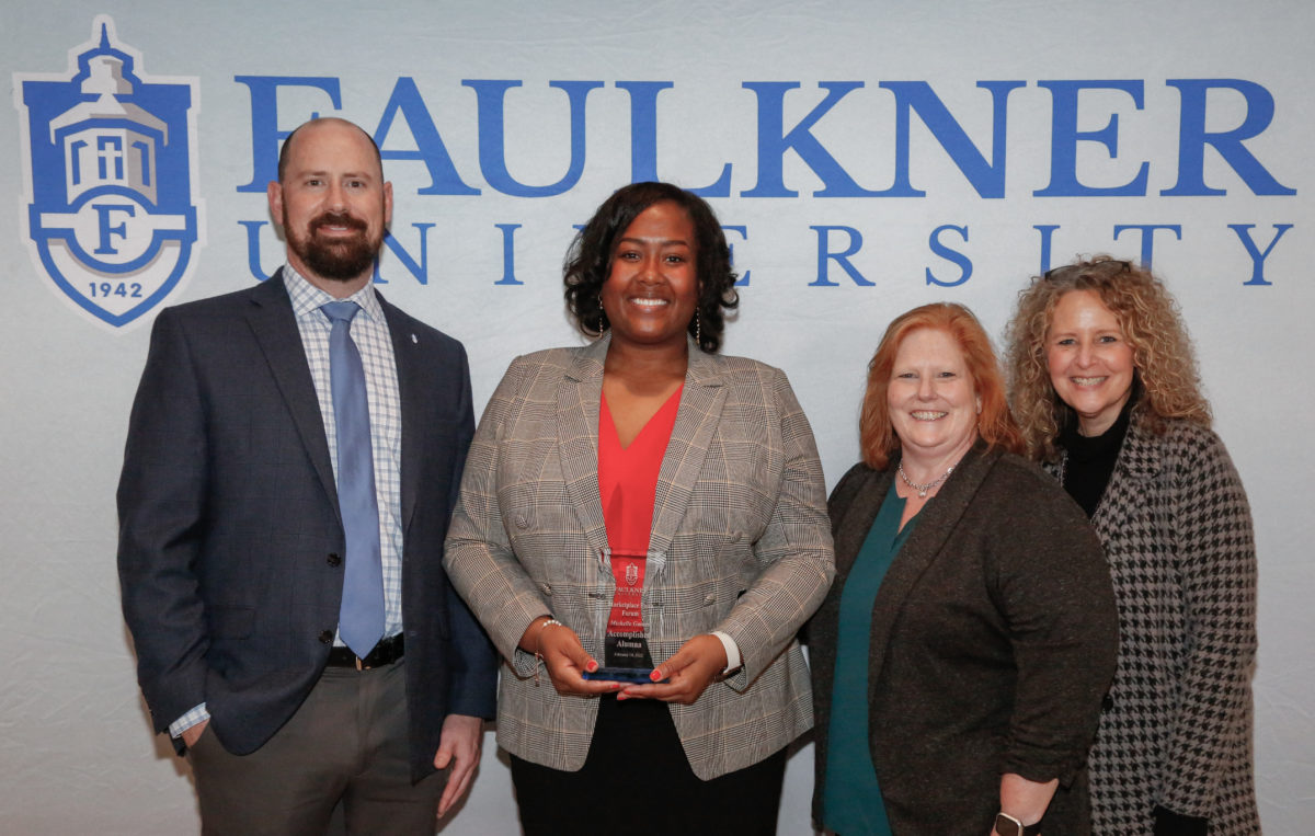 l-r, Justin Bond, Michelle Gaines, Rayla Black, Natasha Kasarjian pose in front of a Faulkner backdrop. Gaines is holding her award from the Marketplace Faith Friday Forums. . 