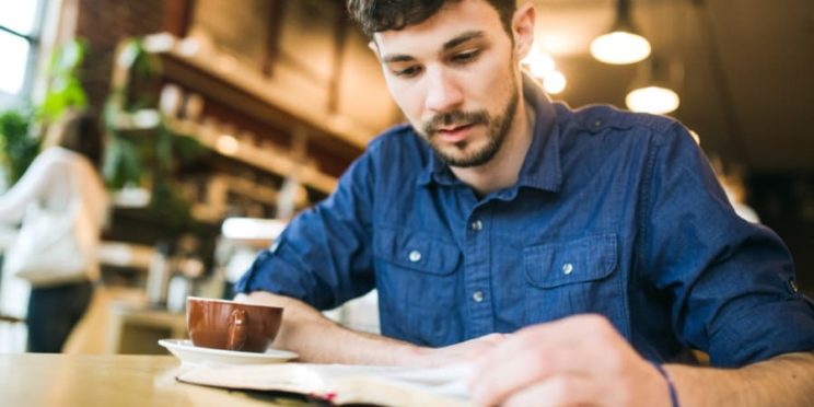 Man reads Bible while drinking coffee