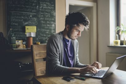 Man sitting at wooden table while participating in online discussion board