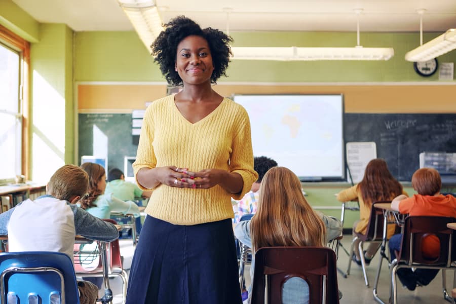 Smiling elementary school teacher standing in front of students