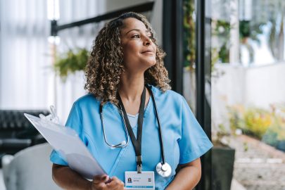 Nurse in scrubs holding clipboard
