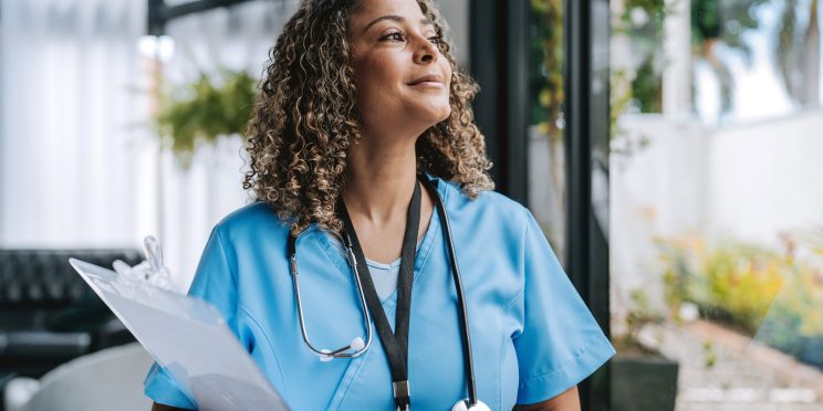 Nurse in scrubs holding clipboard