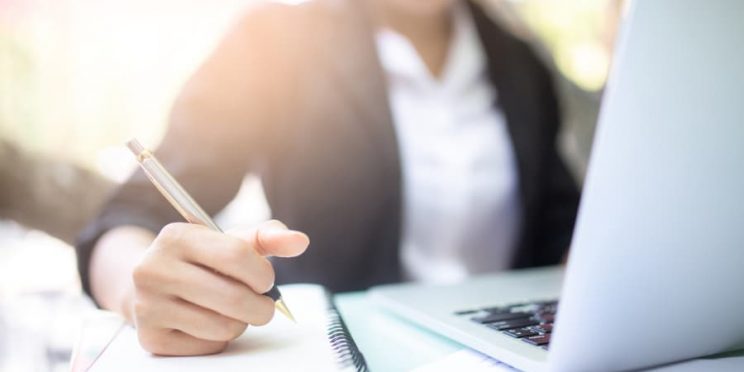 Young woman working with a laptop and notebook