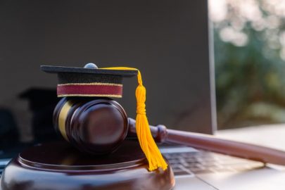 Laptop Beside Judge’s Gavel And Graduation Cap