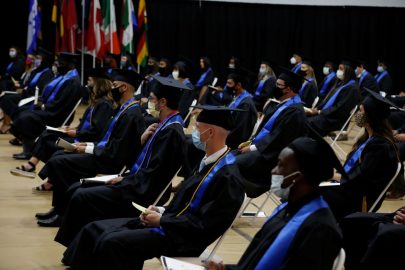 Graduates spaced 6-feet apart wait to walk the stage during 2020 Spring commencement ceremony.