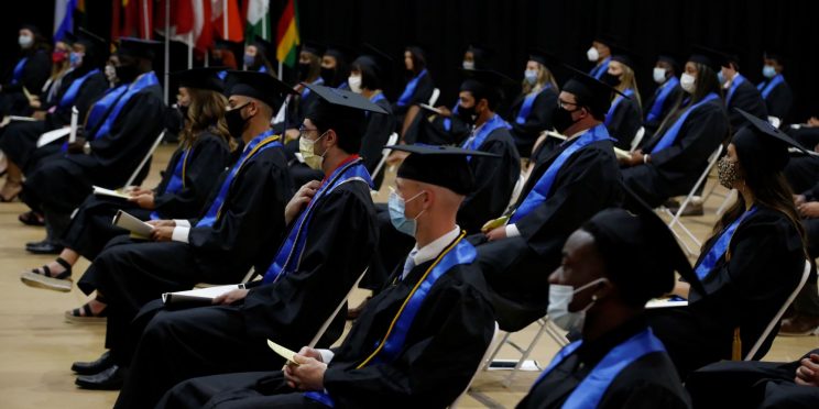 Graduates spaced 6-feet apart wait to walk the stage during 2020 Spring commencement ceremony.