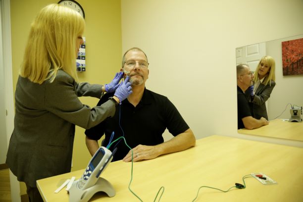 Dr. Amy Ogburn works with an adult patient to administer electrodes to stiumlate jaw muscles