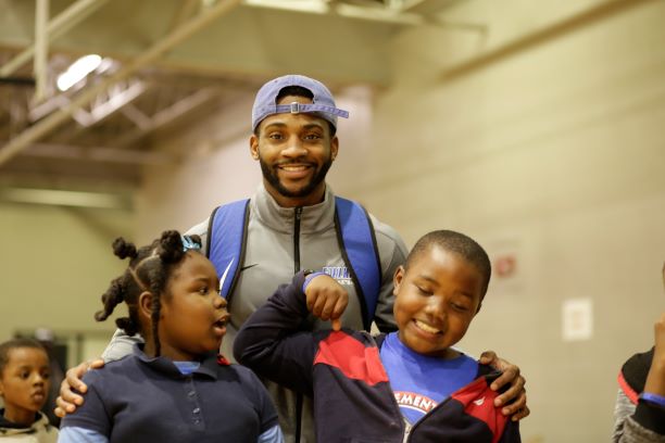 Faulkner student and basketball player, Marquis Grays poses with students from Davis.