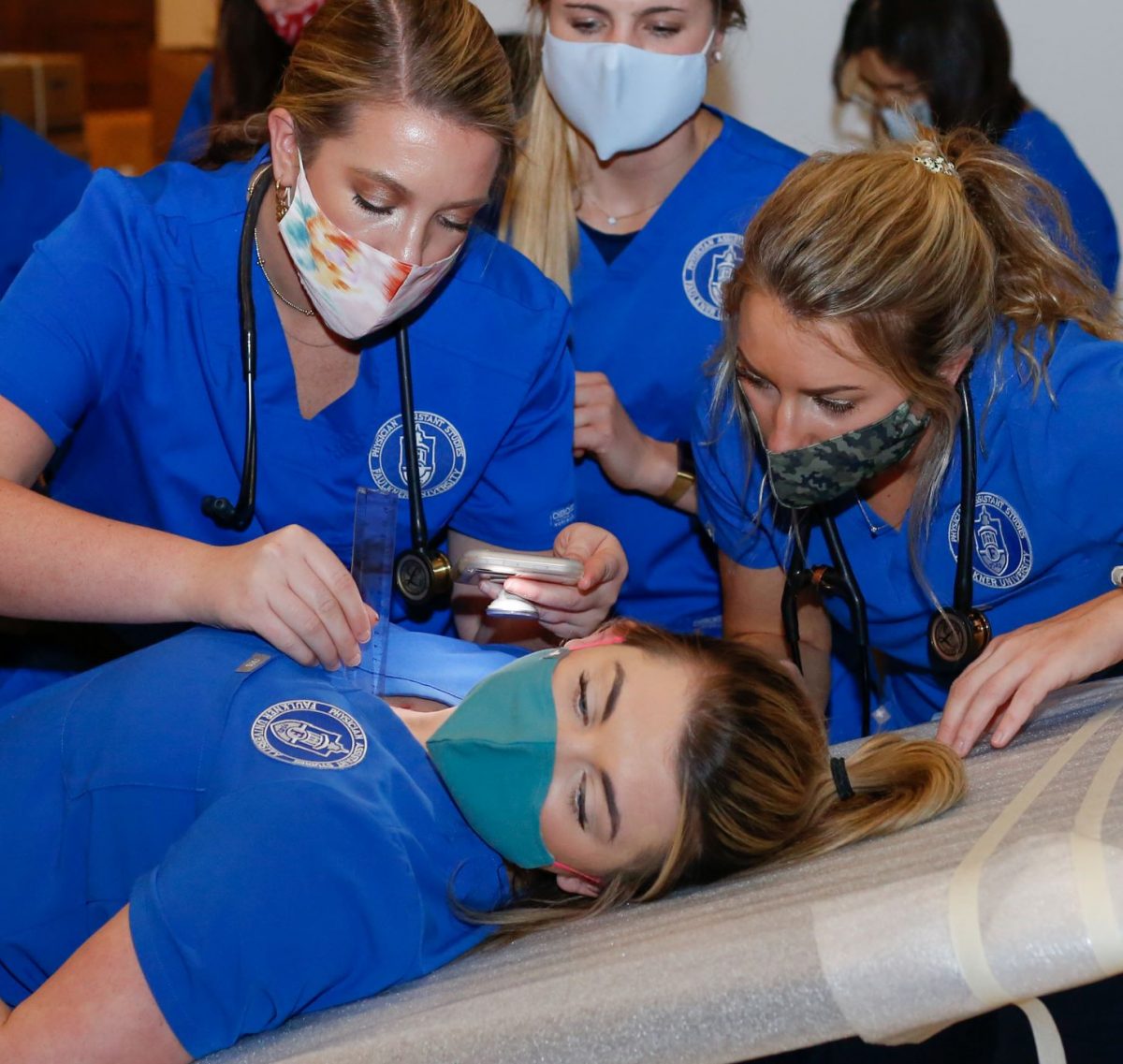 Physician assistant students exam a peer for a clinical exam simulation. 