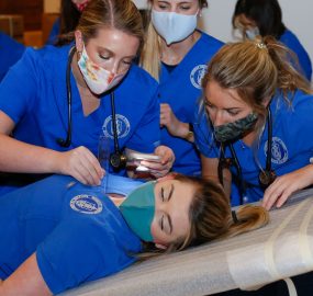 Physician assistant students exam a peer for a clinical exam simulation.