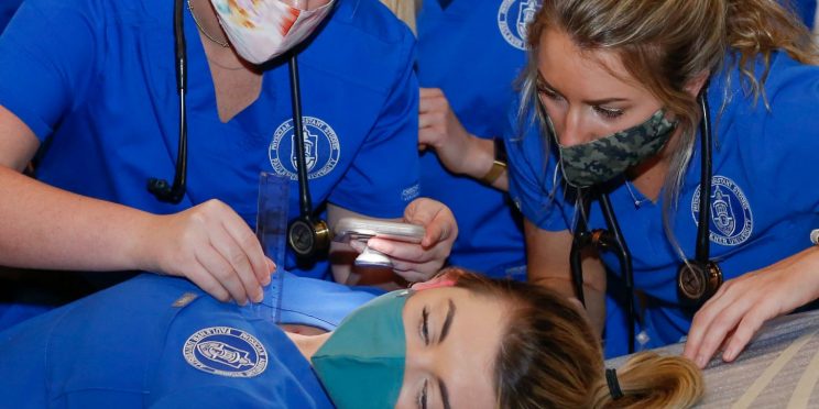 Physician assistant students exam a peer for a clinical exam simulation.