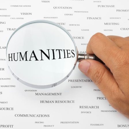 Page with words on it with humanities in center under magnifying glass