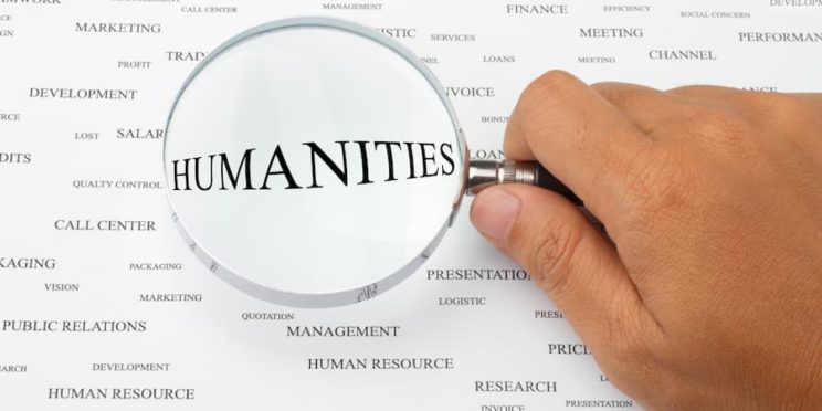 Page with words on it with humanities in center under magnifying glass