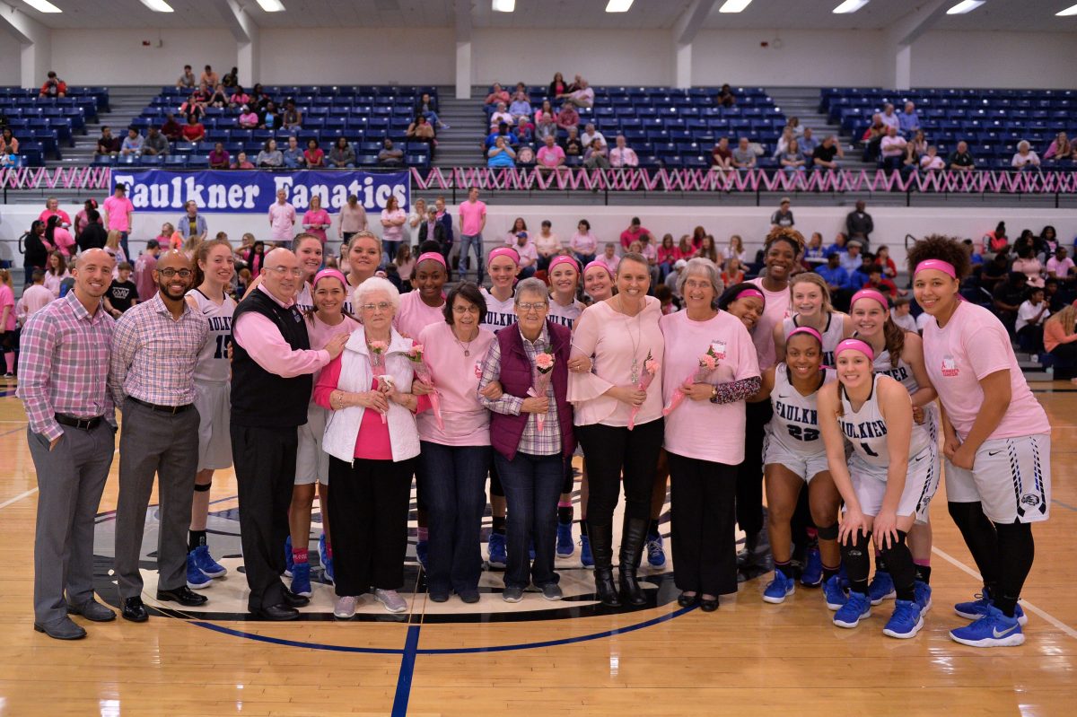 Breast Cancer survivors pose with the Faulkner Women's Basketball team during their PinkOut game in 2019.