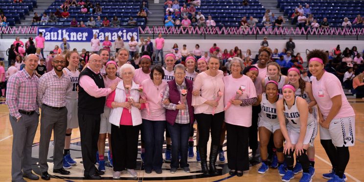 Breast Cancer survivors pose with the Faulkner Women's Basketball team during their PinkOut game in 2019.