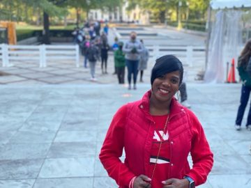 Judge Ruby Davis stands outside in a red coat and a t-shirt with her slogan.