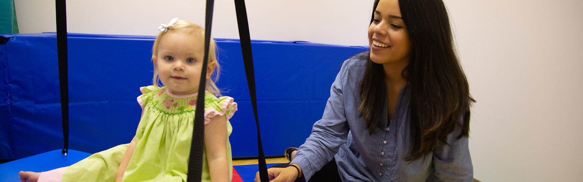 A Faulkner Speech Language Pathology student aiding an infant