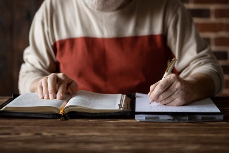 Student reading the bible and taking handwritten notes