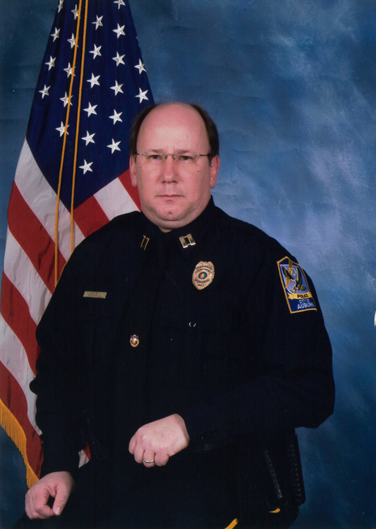 Tommy Carswell poses in front of the United States of America flag wearing his police captain uniform.