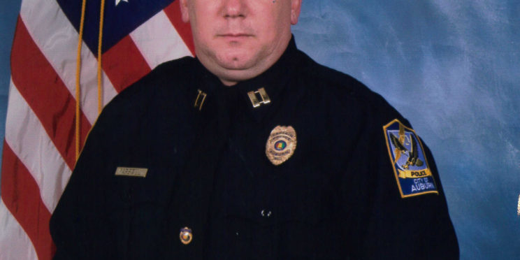 Tommy Carswell poses in front of the United States of America flag wearing his police captain uniform.