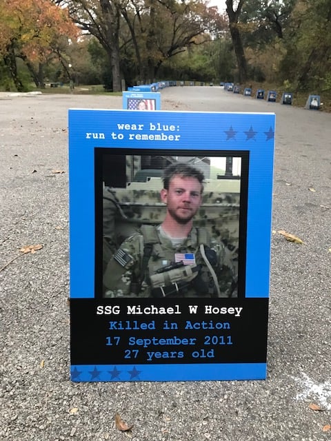 A Picture of SSG Michael Hosey in his combat fatigues is set in a blue frame and placed along a portion of the race pavement.  