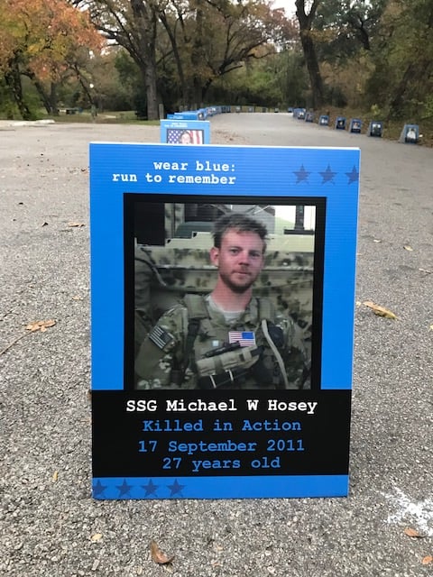 A Picture of SSG Michael Hosey in his combat fatigues is set in a blue frame and placed along a portion of the race pavement.