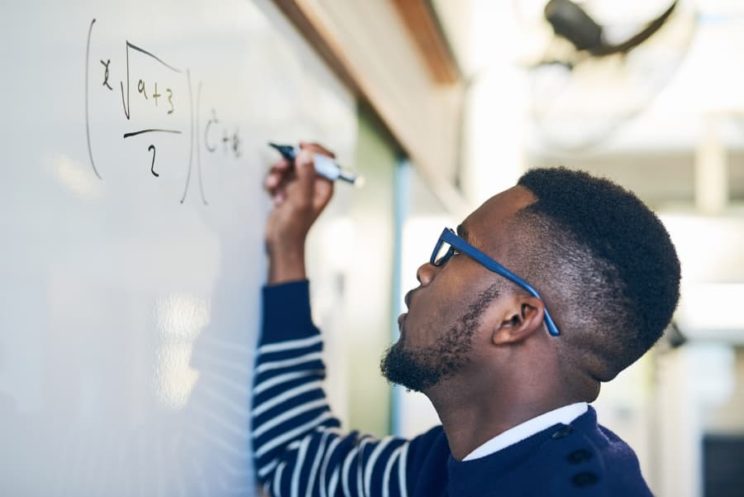 Young man writing on whiteboard in classroom