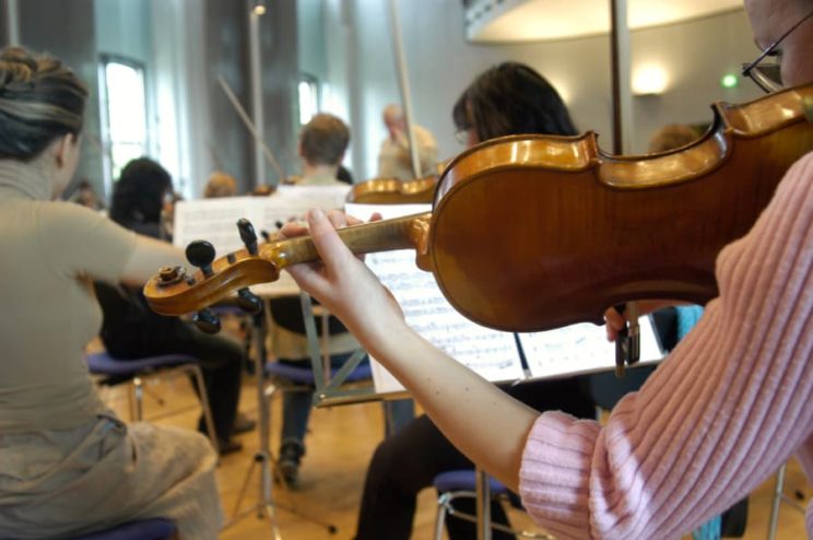 Young woman playing violin in orchestra
