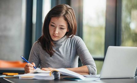 College Student Studying with Notebook and Laptop