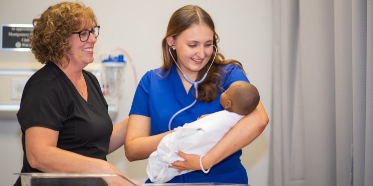 Faulkner university nursing student holding a baby in training