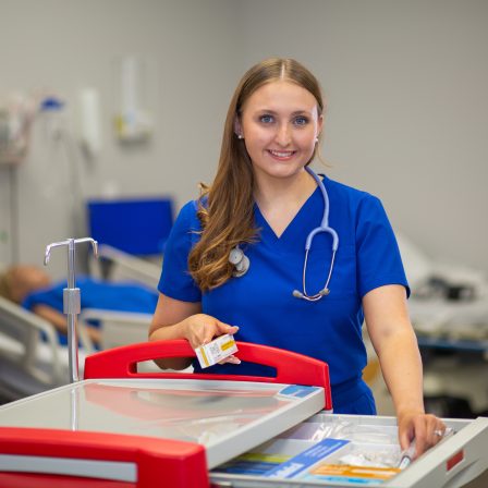 Faulkner university nursing student standing next to medical cart