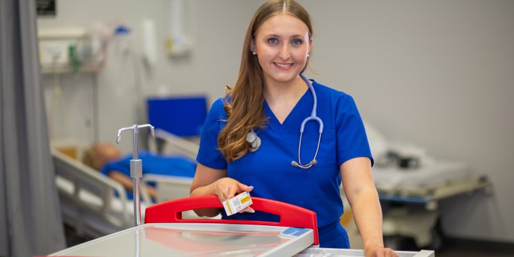 Faulkner university nursing student standing next to medical cart
