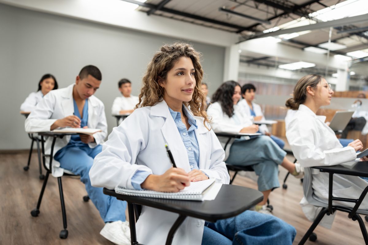 Group of medical students sitting at desks in classroom and taking notes