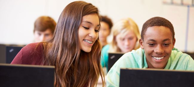 High school students in class on laptops.