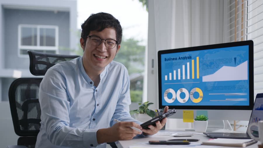Smiling employee working at computer with analytics on screen