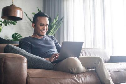 Man on Couch Typing on Laptop