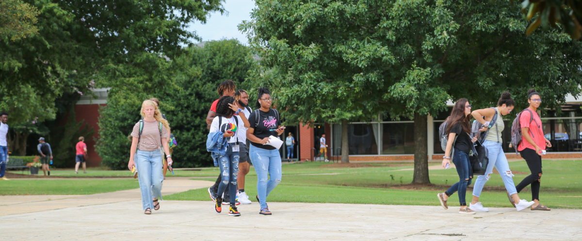 Faulkner students including African American students walk together toward the gym across Faulkner's brick Quad courtyard.