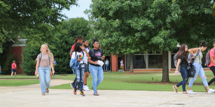 Faulkner students including African American students walk together toward the gym across Faulkner's brick Quad courtyard.