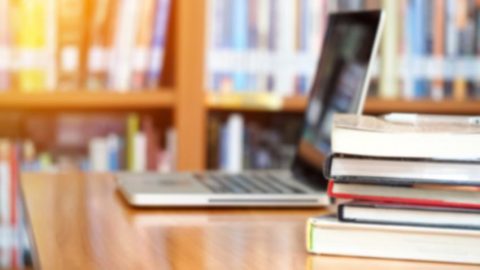 Stack of Textbooks Next to Laptop